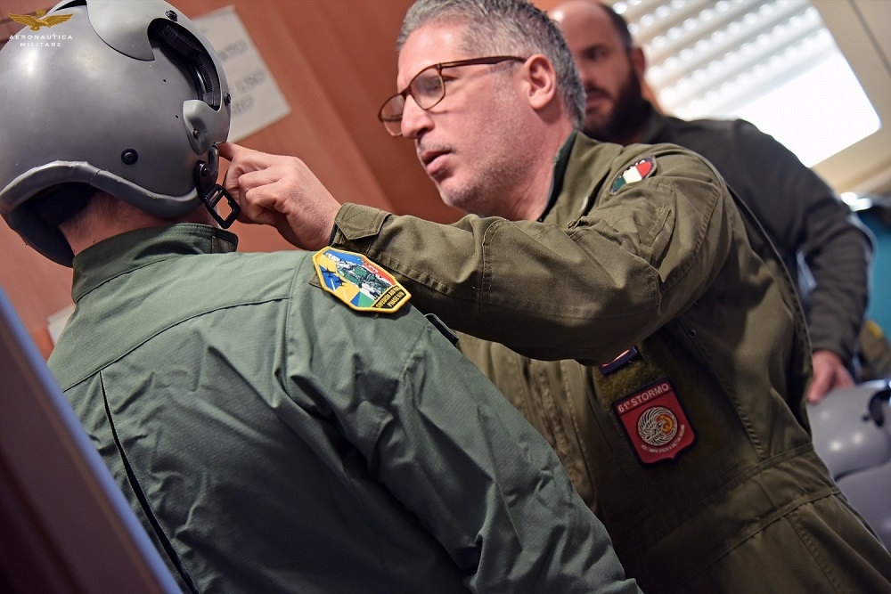 Coronel Vito Conserva, Comandante da 61º Stormo, ajuda um dos cadetes suecos na sala deequipagens de voo do 214º Gruppo. Foto: AMI.
